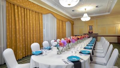 Dining room with a long table, chairs, and vibrant flower decor at Polonia Palace Hotel