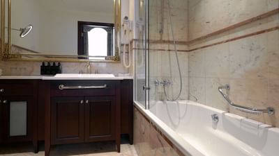Bathroom with marble walls, a bathtub, and a shower stall at Polonia Palace Hotel