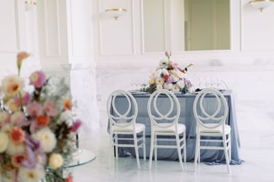 Dining setup with white chairs and a flower decor in a bright room at Polonia Palace Hotel
