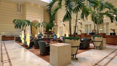 Lobby interior with seating, palm trees, and reception area at Polonia Palace Hotel