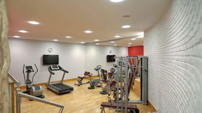 Gym interior with exercise equipment, treadmill, and textured white wall at Polonia Palace Hotel