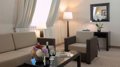 Lounge area in Suit with a beige sofa, armchair, and flowers on the coffee table at Polonia Palace Hotel