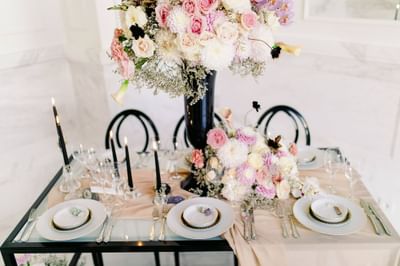 Dining table setting with a floral decor, chairs, and lit candles at Polonia Palace Hotel