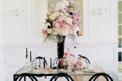 Dining table setting with a floral decor, chairs, and lit candles at Polonia Palace Hotel