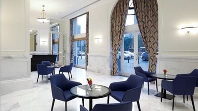 Dining area with blue chairs, marble floors, large windows and patterned curtains at Polonia Palace Hotel