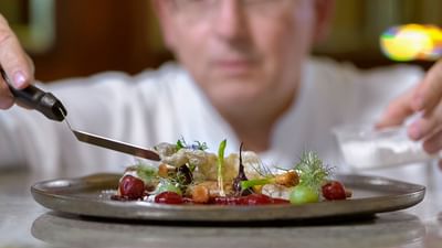 Chef plating a dish with tweezers in Polonia Restaurant at Polonia Palace Hotel