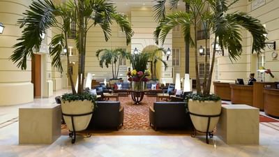 Hotel lobby with seating, palm trees, and reception area at Polonia Palace Hotel