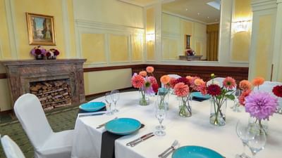 Dining room with a fireplace, turquoise plates, and flower decor at Polonia Palace Hotel