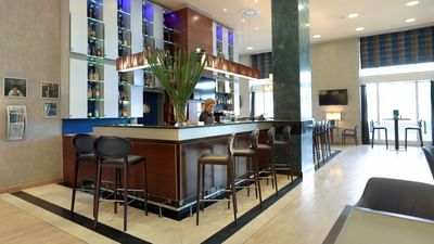 Lobby bar with bar counter, seating, and illuminated shelves at Polonia Palace Hotel